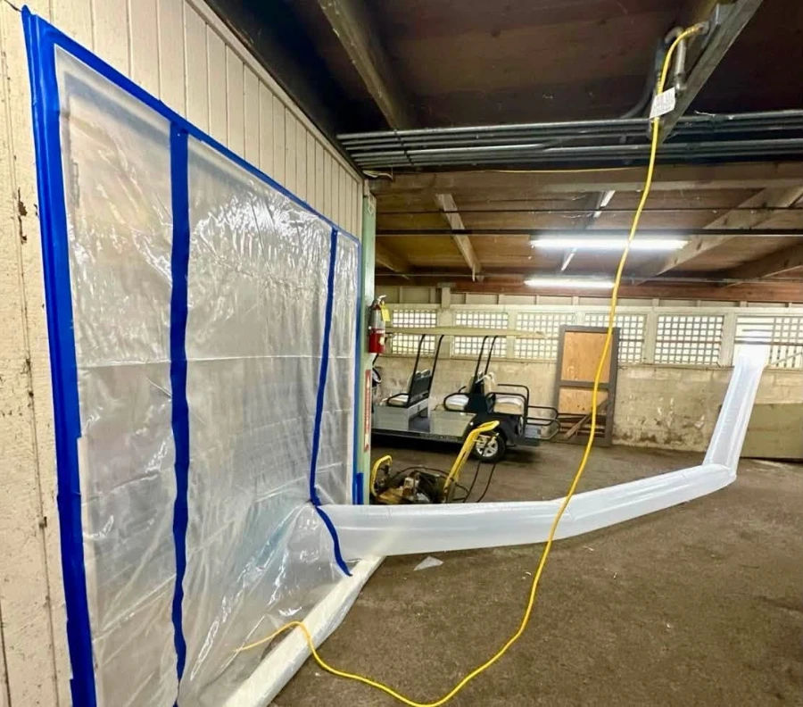 Technician sealing off a work area with plastic sheeting before mold removal