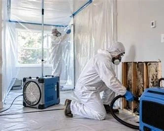 Technician setting up plastic containment sheeting around a work area before mold remediation